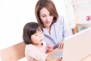 Asyalı bir kadın ve bir çocuk dizüstü bilgisayar kullanıyor, online eğitim kavramı