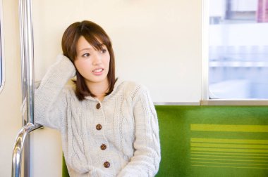 Trende oturan genç Asyalı kadın.