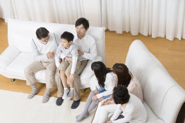 Aile beyaz koltuklarda birlikte oturuyor.