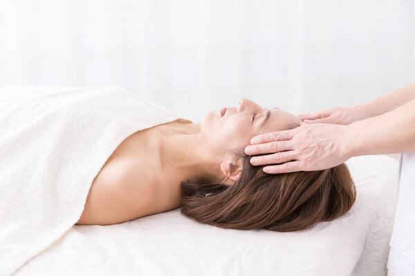 Красивая японская женщина делает массаж лица в спа-салоне