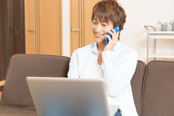 woman using laptop and talking on the phone at home