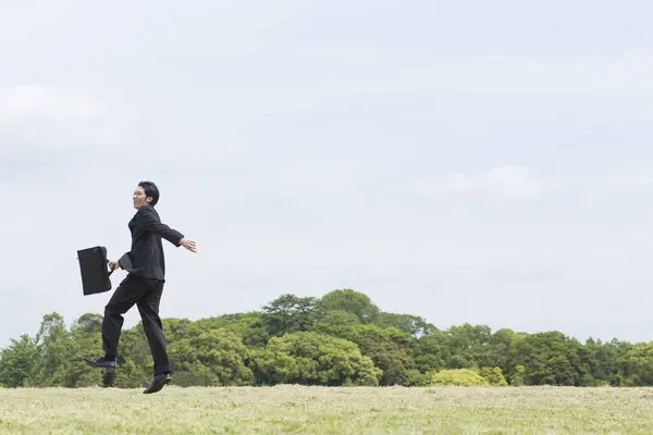 young man in suit running through the field