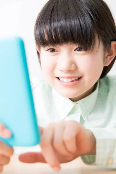 スマートフォンを使った笑顔の日本人少女 — ストック写真
