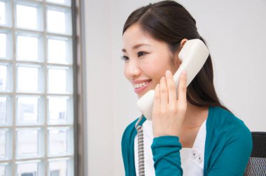 Genç Asyalı iş kadını telefonda konuşuyor.