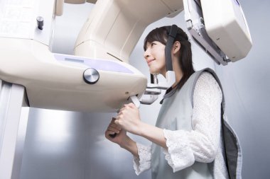 Kadın hasta dişçi tomografisi yapıyor. Dişlerinin röntgenini çeken kadın ortodontik röntgen makinesinin yardımıyla klinikte.