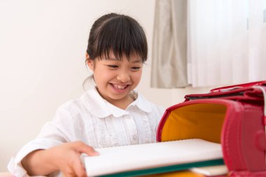 Asyalı kız öğrenci okulda çantasını açtı.