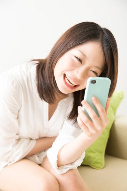 Beyaz üzerine izole edilmiş akıllı telefon kullanan güzel Asyalı bir kadının portresi.
