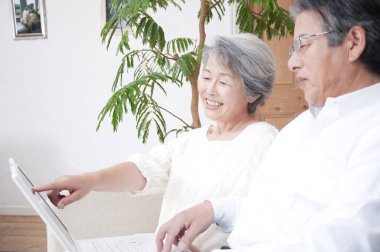 Üst düzey Japon çift evde dizüstü bilgisayar kullanıyor.