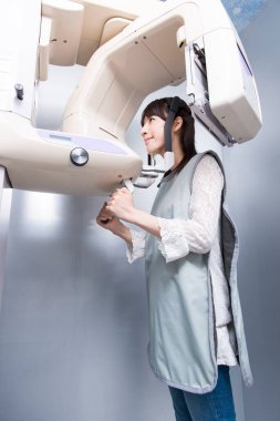Kadın hasta dişçi tomografisi yapıyor. Dişlerinin röntgenini çeken kadın ortodontik röntgen makinesinin yardımıyla klinikte.