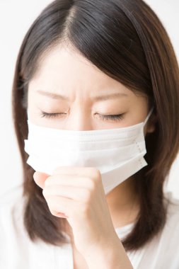 Soluk maskeli hasta bir Asyalı kadının portresi beyaza izole edilmiş.