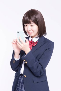 Akıllı telefon kullanan gülümseyen Japon öğrencinin stüdyo portresi