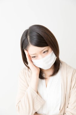 Soluk maskeli hasta bir Asyalı kadının portresi beyaza izole edilmiş.