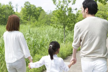 Mutlu Asyalı anne, baba ve kız parkta birlikte vakit geçiriyorlar.