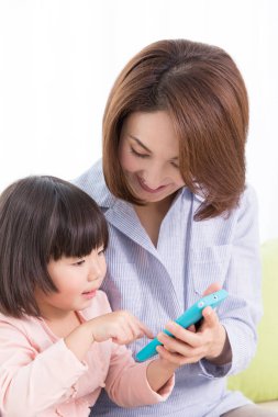 Evde cep telefonu olan Asyalı bir anne ve kız.