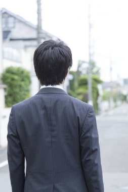 Sokakta duran takım elbiseli iş adamının arkadan görünüşü