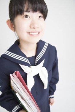 Asyalı kız beyaz arka plan üzerine kitapları elinde tutuyor.