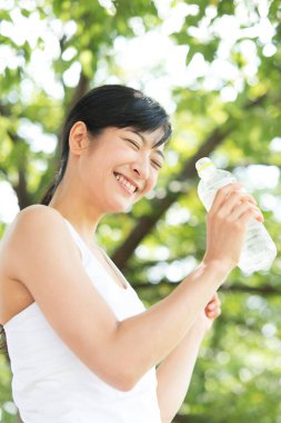 Yaz parkında koşu yaparken su içen güzel Japon kadın. 