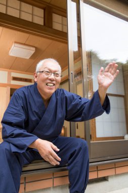 japanese senior man in traditional clothes waving hand 