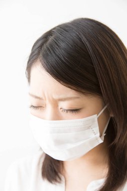 Soluk maskeli hasta bir Asyalı kadının portresi beyaza izole edilmiş.