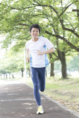 Sportif Japon adam yaz parkında koşuyor. 