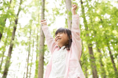 Mutlu Asyalı kız ormanda oynuyor.