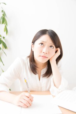 Genç Asyalı kadın evde ders çalışıyor.