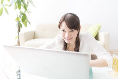 Evde dizüstü bilgisayar kullanan Asyalı genç bir kadın. 