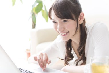 Evde dizüstü bilgisayar kullanan Asyalı genç bir kadın. 