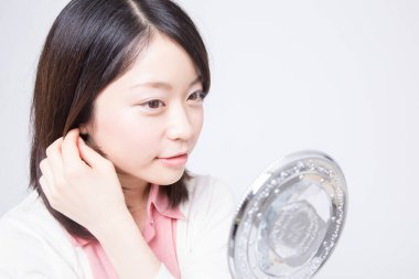 Genç Asyalı kadın aynaya bakıyor. 