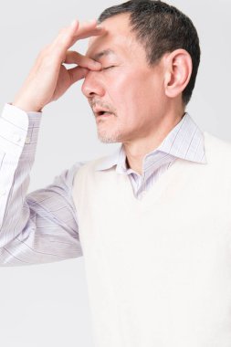 Beyaz arka planda acıdan muzdarip olgun Asyalı adamın portresi.