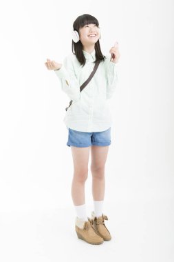 Sıradan giyinmiş Asyalı bir kızın portresi müzik dinliyor.