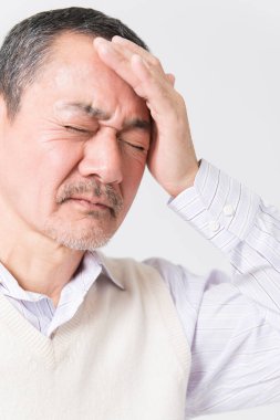 Beyaz arka planda acıdan muzdarip olgun Asyalı adamın portresi.