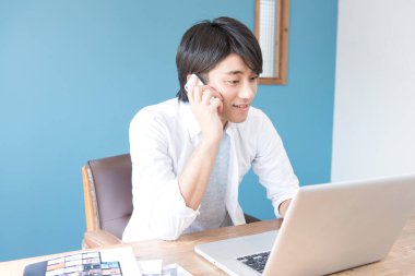 Genç Asyalı adam ofiste çalışıyor. 