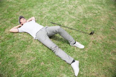 Adam golf sahasında yatıyor.