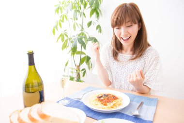 Genç kadın spagetti yiyor ve gülümsüyor.