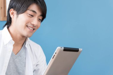 Tablet kullanan gülümseyen genç adam.