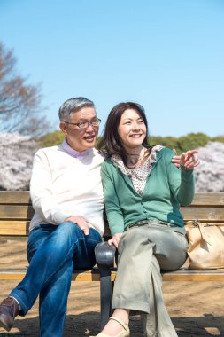 Güzel Asyalı olgun çift çiçek açan kiraz ağaçlarına karşı poz veriyor.