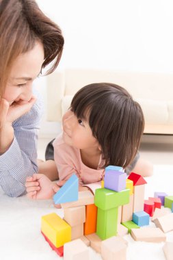 Asyalı anne ve küçük kızı birlikte oynuyorlar.