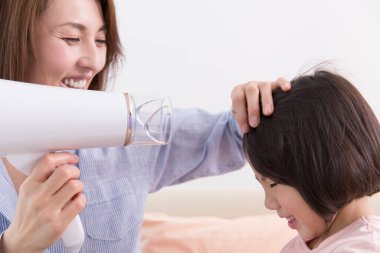 Saç kurutma makinesiyle Asyalı anne ve kızı. 