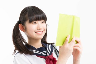 Okul üniformalı, beyaz arkaplan üzerine kitabı olan güzel bir öğrencinin portresi.