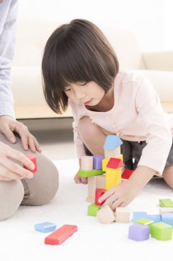 Asyalı anne ve küçük kızı birlikte oynuyorlar.