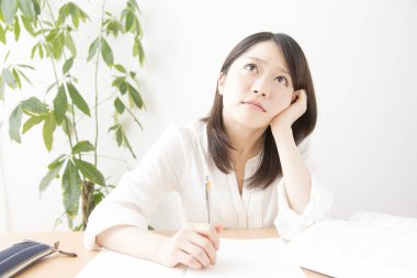 Genç Asyalı kadın evde ders çalışıyor.