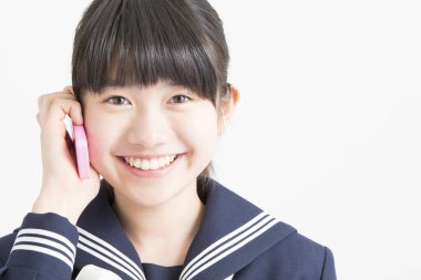 Okul üniformalı genç Asyalı kızın portresi akıllı telefondan konuşuyor.