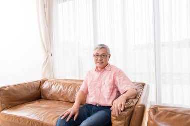 Evdeki oturma odasında dinlenen yaşlı Asyalı adamın portresi.