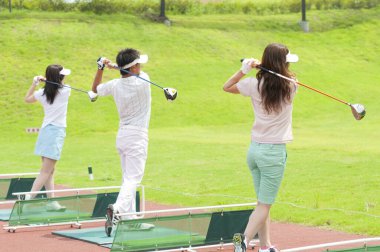 Genç Asyalı kadın ve erkek birlikte golf oynuyorlar. 