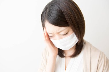 Soluk maskeli hasta bir Asyalı kadının portresi beyaza izole edilmiş.