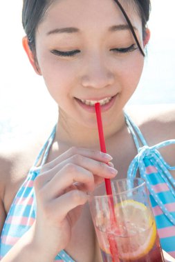 Genç Asyalı kadın kokteyl içiyor.