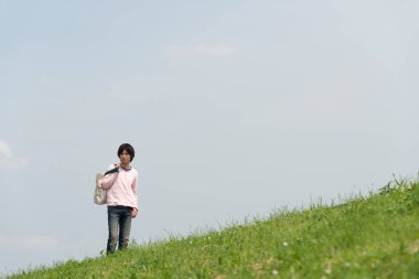 Genç adam yaz parkında yürüyor.