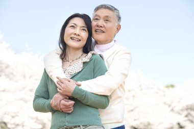 Güzel Asyalı olgun çifti ağaçlarla parka kapatın.