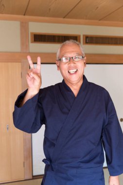 senior man in kimono  showing victory gesture 